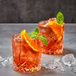 two glasses of aperol soda cocktail on grey table